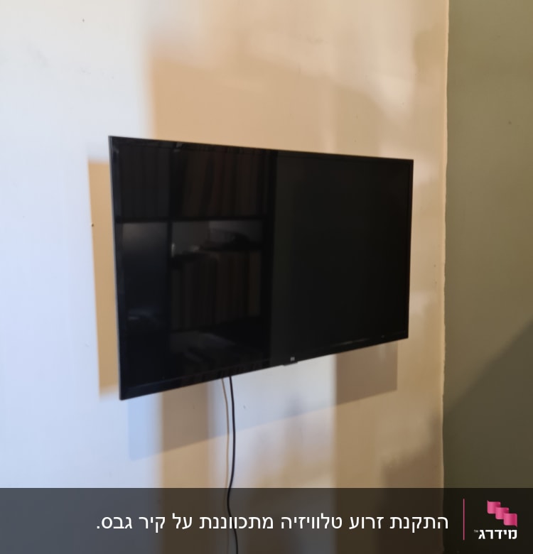 טלוויזיה תלויה על הקיר עם כבל חשמל